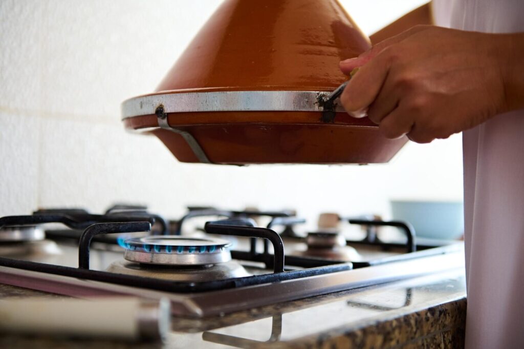 Closeup housewife holding clay pot tagine stove cooking delicious meal home kitchen 328764 10943